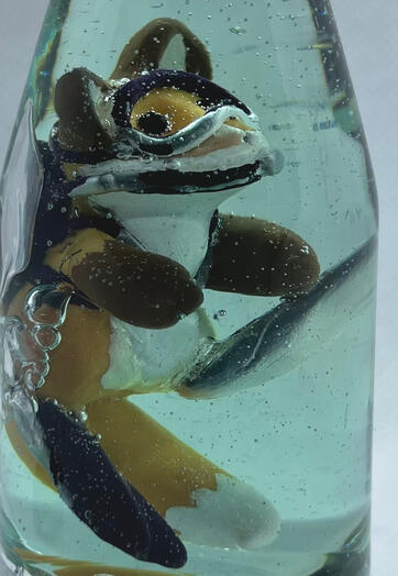 A tiny red fox wearing scuba gear, treading water in a bottle. Photo shows the bubbles from his equipment and swimming.
